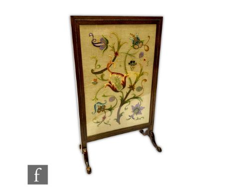 A 1920s oak framed firescreen raised to shallow cabriole legs with pad feet, the central panel detailed with a needlework flo