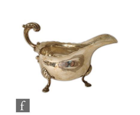 A hallmarked silver sauce boat of plain form raised on three stepped pad feet and terminating in acanthus capped flying scrol