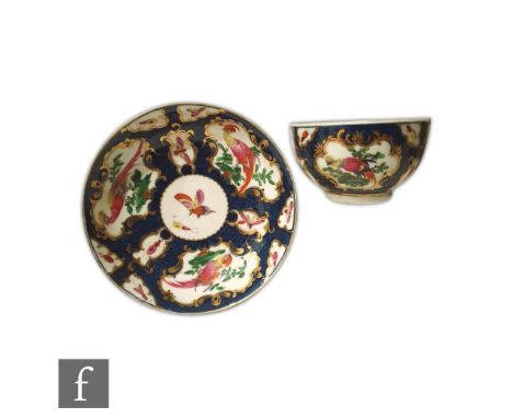 An 18th Century Worcester teabowl and saucer decorated with cartouche panels of fancy birds and insects against a blue scale 