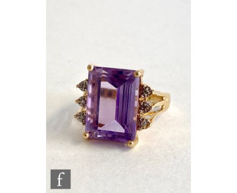 A 14ct amethyst and diamond ring, central emerald cut amethyst length 14mm, flanked by three diamonds to either side, all to 
