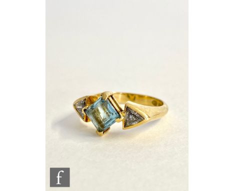 An 18ct hallmarked aquamarine and diamond three stone ring, central off set square cut aquamarine flanked by a triangle cut d