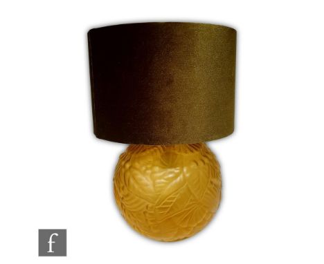 A 1930s pressed glass table lamp of spherical form, relief moulded with stylised flowers and foliage to a frosted amber groun