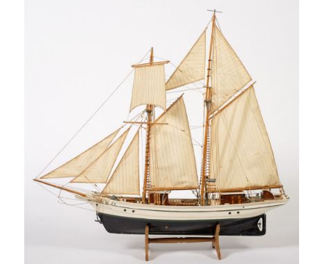 A scale model of a trawler:, fully rigged over planked deck with wheelhouse, davits and lifeboat, white gunwale and black hul