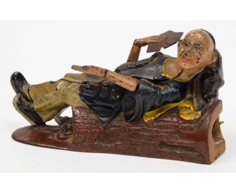 A Reclining Chinaman cast iron money bank by J E Stevens:, the recumbent figure with one hand out the other  holding cards to