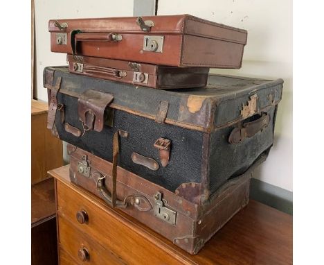 A vintage black travelling trunk with brown leather handles and strapping. together with a vintage brown leather suitcase and