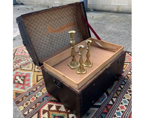 An early 20th century wood bound dome top trunk, covered in black leatherette, with metallic and stud decoration, opening to 