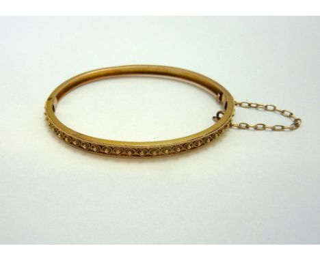 AN EARLY 20TH CENTURY ROSE GOLD BANGLE, with granulated and rope twist texture, to the plain hinged bangle with safety chain,