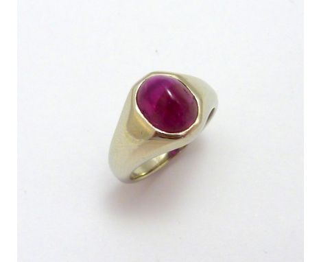 A RUBY RING, the oval shape cabachon ruby within a white metal surround, ring size H 1/2