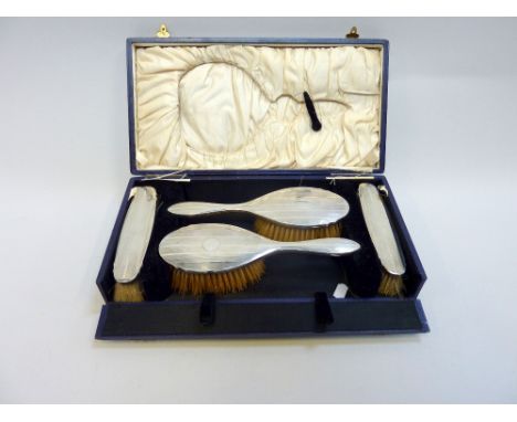 A CASED SILVER MOUNTED DRESSING TABLE SET, Birmingham 1928, with engine turned decoration, comprising two pairs of brushes, g