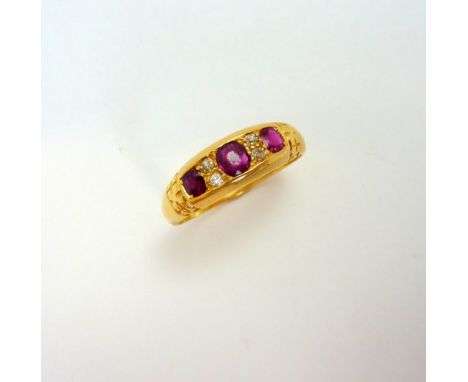 AN 18CT GOLD RUBY AND DIAMOND RING, with three rubies and old cut diamond accents, with engraved cross detail to the plain ta