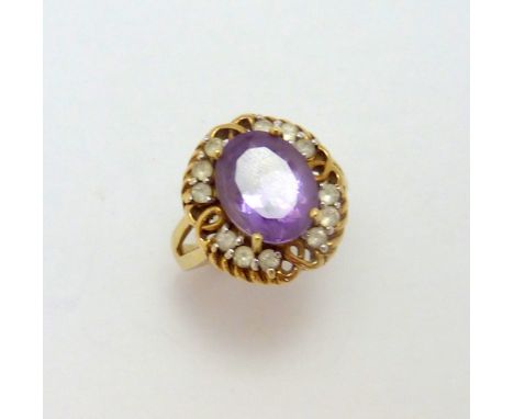 A 9CT GOLD AMETHYST AND CUBIC ZIRCONIA CLUSTER RING, with central oval shape amethyst within a twisted surround and cubic zir