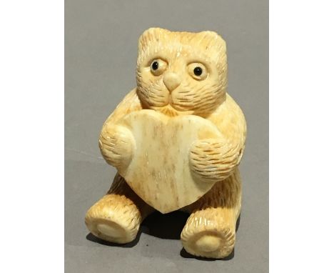 A bone netsuke formed as a bear with a heart