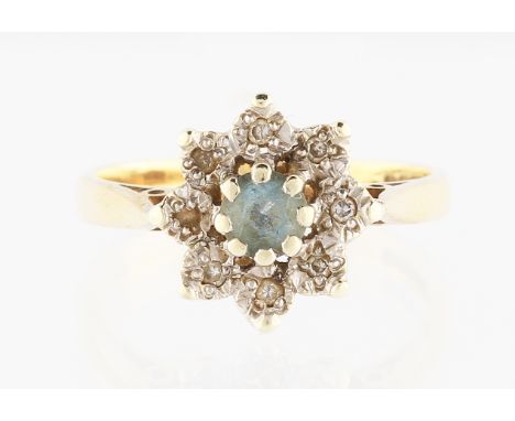 A 9ct yellow gold aquamarine and diamond flower head design ring, set with a round cut aquamarine, surrounded by a border of 