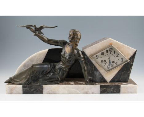 A French Art Deco mantle clock, depicting a seated bronzed spelter female reclining figure, a bird on her arm, mounted on an 