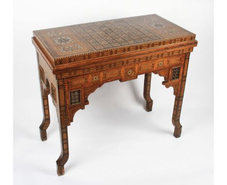 A late Victorian Anglo Indian games table with extensively inlaid body and interior, the hinged lid revealing similar inlaid 