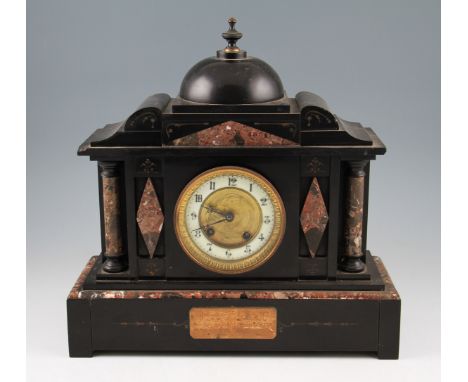 A 19th Century French slate and marble mantel clock with column end supports and central domed top with indistinct inscriptio