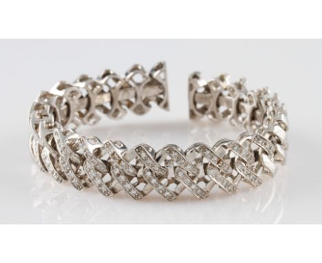 A white metal diamond set bangle, featuring articulated links around a bangle core allowing the bangle to be expandable, half