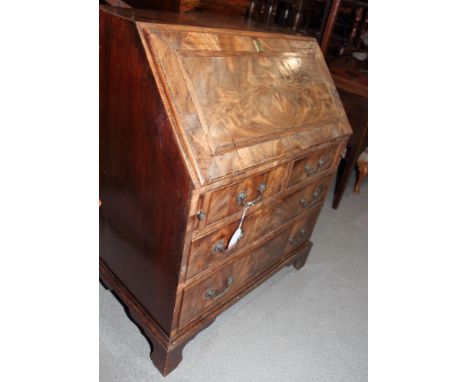 A Georgian crossbanded mahogany bureau, sloping fall flap enclosing drawers, pigeon holes and central cupboard, fitted two sh