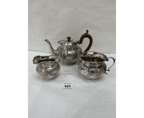 An Edward VII silver three piece tea service, comprising a foliate repousse chased teapot, milk jug and sucrier Birmingham 19