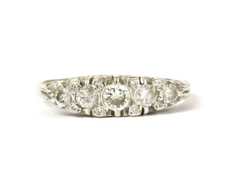 An 18ct white gold five stone diamond ring, a row of graduated brilliant cut diamonds, claw set to the scrolling carved-style