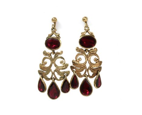A pair of 9ct gold flat cut garnet drop earrings, a pierced foliate panel suspending three pear flat cut garnet drops, surmou
