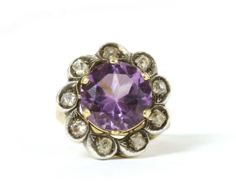 A silver and gold, amethyst and diamond cluster ring, a circular mixed cut amethyst, approximately 12mm diameter, claw set in
