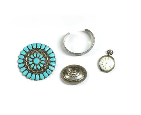 A Navajo silver turquoise brooch, a central cluster of cabochon turquoise, to repoussé crescent border, and outer row of cabo