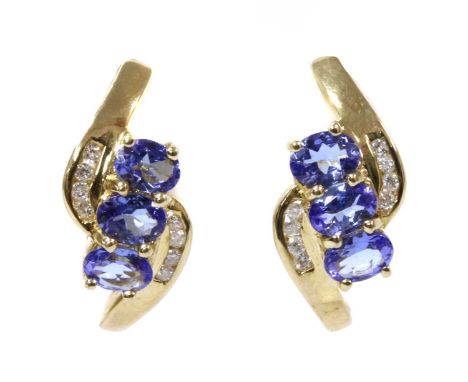 A pair of gold tanzanite and diamond stud earrings, with a row of oval mixed cut tanzanites, approximately 4 x 3mm, claw set 