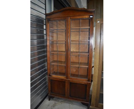 An early 20th century oak book case having leaded light doors with under cupboard