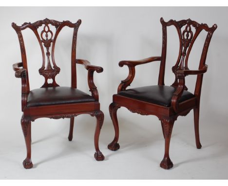 A set of twelve Chippendale style carved mahogany dining chairs, each with typical pierced splatbacks and low floral relief c