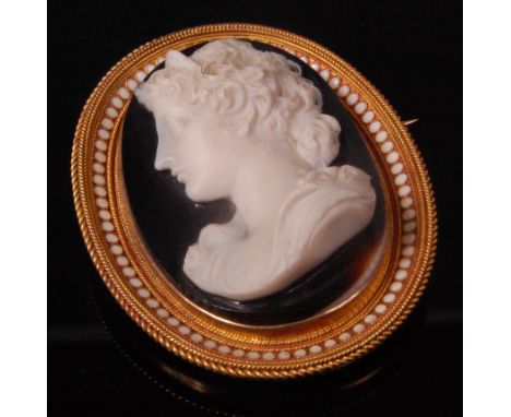 A Victorian carved agate and pinchbeck mounted brooch, depicting a profile portrait of a maiden, the mount being white enamel