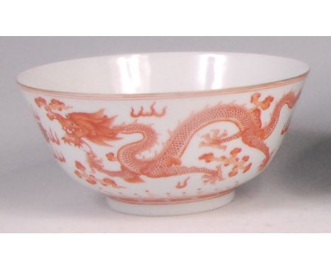 A Chinese white porcelain footed bowl, painted in copper red with two pairs of five clawed dragons guarding sacred jewels aga