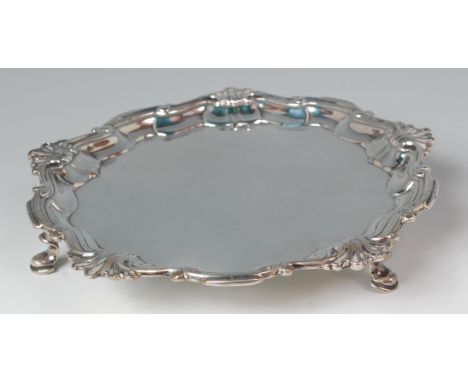 A George II silver card waiter, having a raised piecrust rim in the Rococo taste, on scroll hoof feet, 13.3oz, maker John Swi