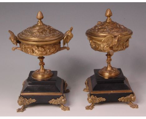 A pair of late 19th century French gilt bronze pedestal urns and covers, each cast with hunting scenes and raised on tiered b