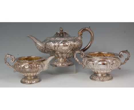 A George IV silver three piece tea service, comprising; pedestal teapot, twin handled sugar and cream, each profusely worked 