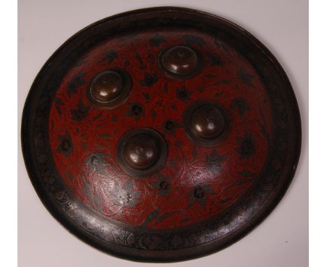 An Indo-Persian metal dhal shield, of convex form, with four domed bosses, decorated with trailing flowers and foliage on a r