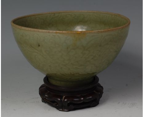 A Chinese carved celadon bowl, probably Ming Dynasty (1368-1644), decorated to both interior and exterior with flowers, the f