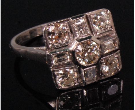 An Art Deco 18ct white gold diamond cluster ring, arranged as a centre raised brilliant with smaller sunken brilliants to eac