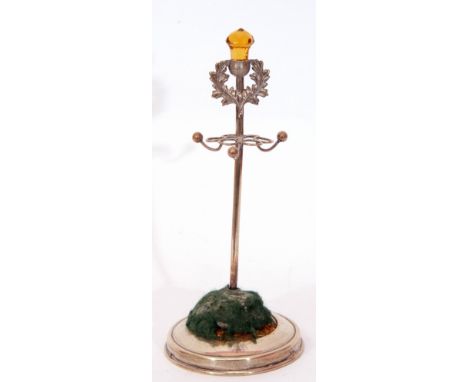 George V hat pin cushion stand, the central stand in the form of a Scottish hat pin with a thistle finial set with a faceted 