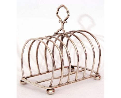 Late Victorian six slice toast rack, the wirework design with central carrying ring handle on a rectangular frame, raised on 