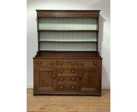 A small 18th century country oak dresser, the three height plate rack with projecting cornice and later panelled back, the ba