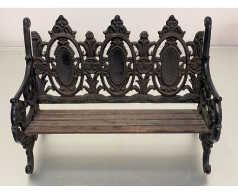 A miniature cast iron bench after a Coalbrookdale design, with slatted wooden seat. 27.5cm by 41cm by 22cm