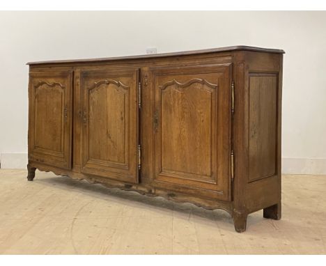 A French Provincial oak sideboard, c. 1800, the two plank top with channel back and moulded edge over three fielded arched pa