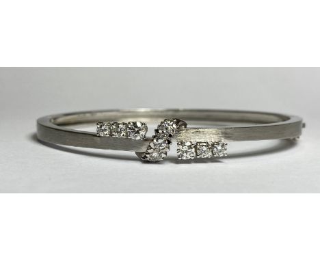 An 18ct&nbsp; white gold, diamond-set bangle, the hinged oval bangle claw-set with twin bands of three graduated round brilli