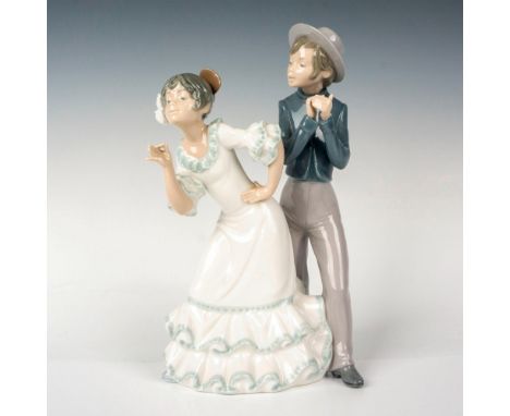 A porcelain figurine depicting a couple side by side with the woman in a white dress and the man in a blue shirt, gray pants,