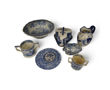 A group of blue and white ceramics to include Ironstone cheese dome and jug, a basin and twin handled cups, largest 36cm in d