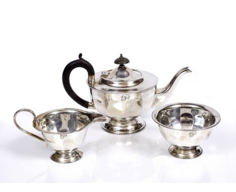 AN ART DECO STYLE THREE PIECE SILVER TEA SET, the circular teapot with panelled sides, domed hinged lid, ebonised handle and 