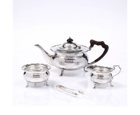 AN EDWARDIAN THREE PIECE SILVER TEA SET, the circular teapot with wavy rim standing on three feet with a wooden handle with m