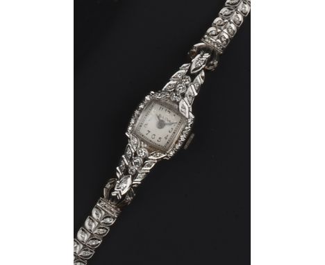 A LADY'S DIAMOND SET COCKTAIL WATCH BY BULOVA, the silvered cushion-shaped dial with Arabic numerals and outer minute scale, 