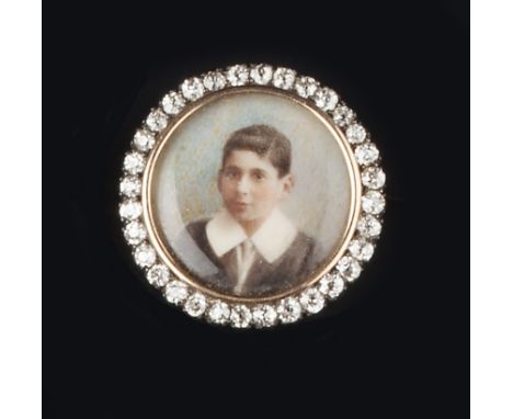 A LATE VICTORIAN PORTRAIT PANEL BROOCH, the circular panel depicting the portrait of a boy in formal dress, framed by old-cut